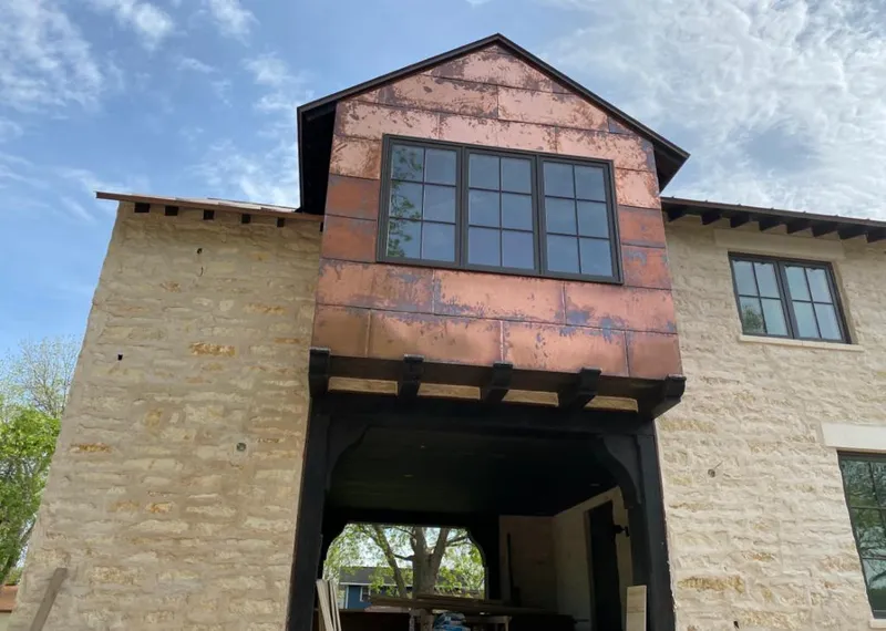 Copper metal panel facade on a stone building for Roof Repair in Green Oak